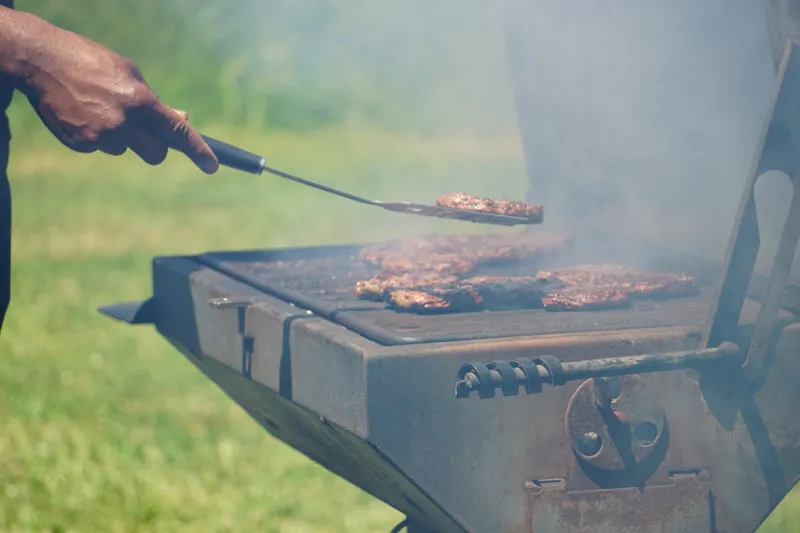 a person is cooking hamburgers on a grill